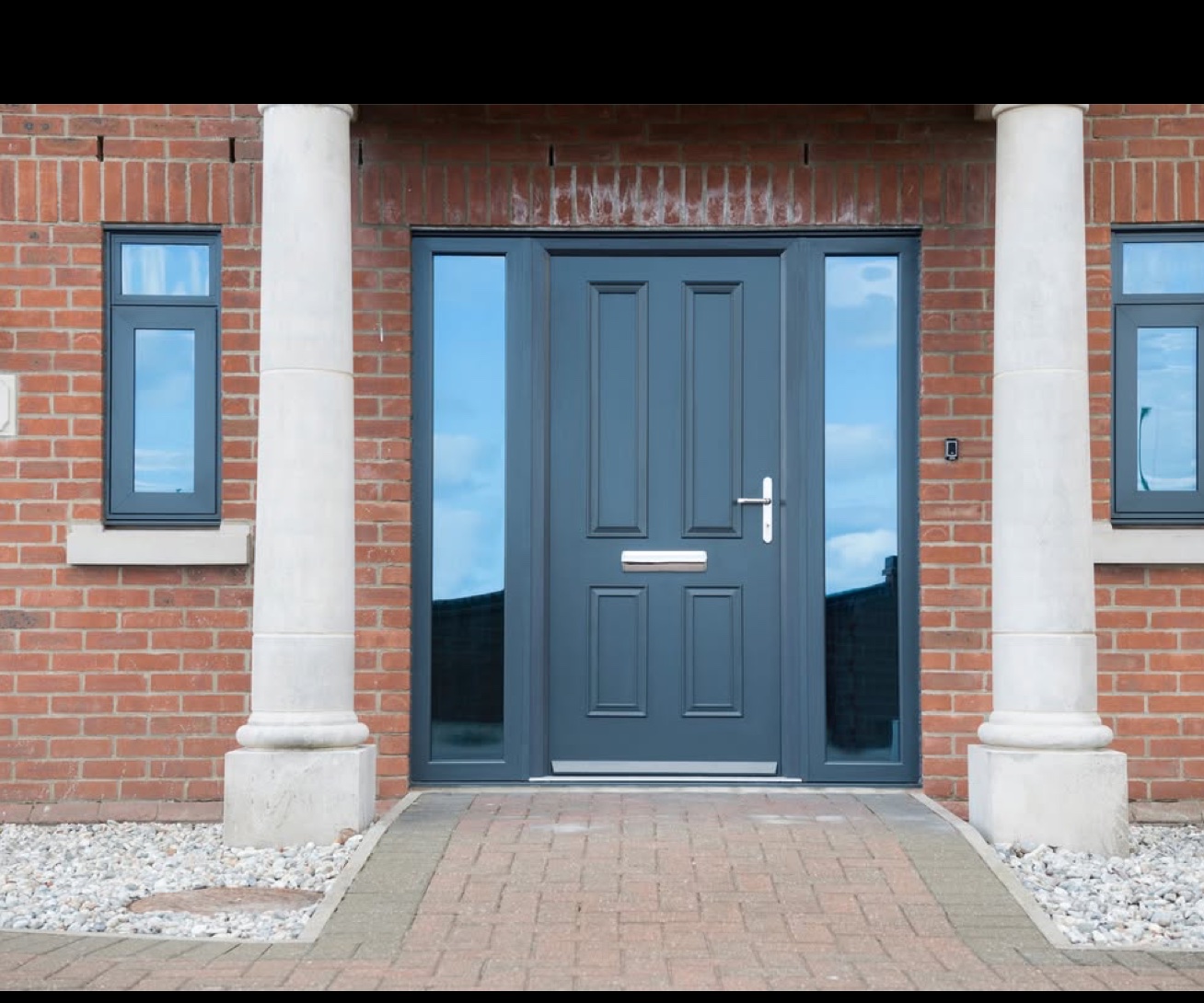 Grey composite door with twin sidelights between stone pillars