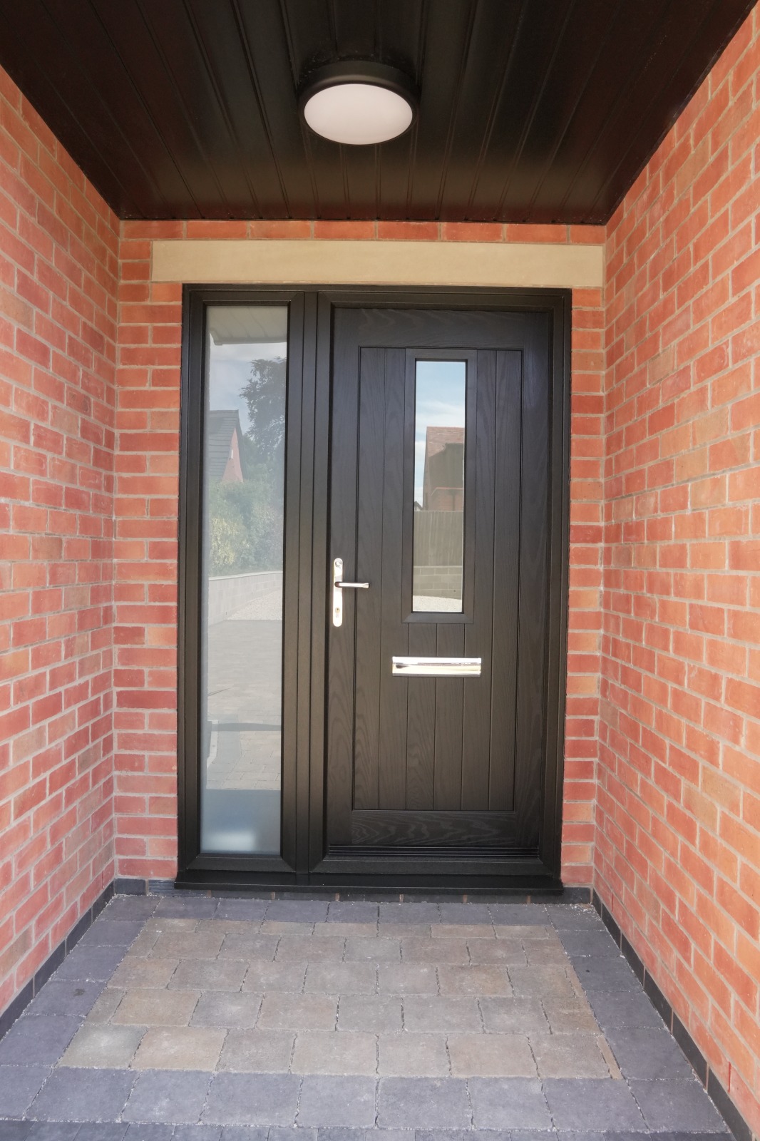 Black composite entrance door with sidelight in red brick porch